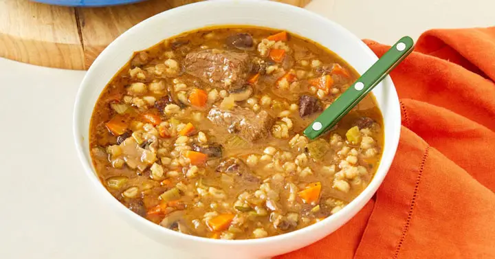A white bowl filled with Beef and Barley Soup look delicious